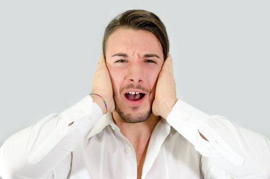 Irritated, frustrated, stressed guy covering his ears, too much noise
