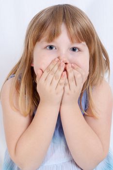 Portrait of a cute little girl covering her mouth with hands