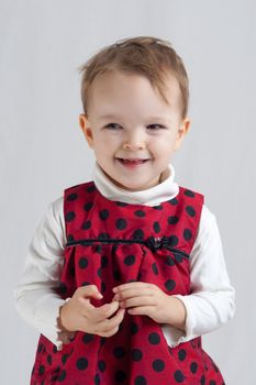 portrait of an smiling little blonde girl wearing a red dress with black spots