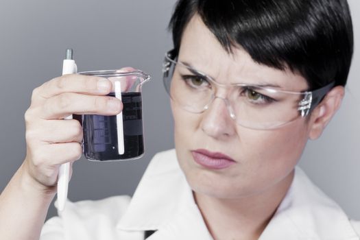 A female medical or scientific researcher or doctor looking at a liquid clear solution in a laboratory.