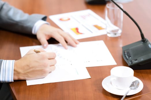 Businessman writing on paper notes, On the table is a cup of coffee and a device for communication at the conference