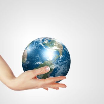 Globe in human hand against blue sky. Environmental protection concept. Elements of this image furnished by NASA