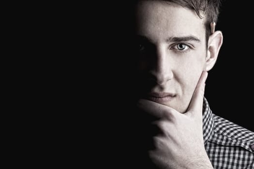 Portrait of young man thinking, black background
