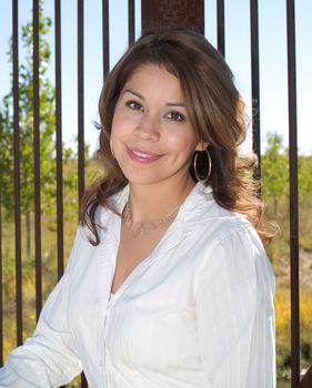 Young hispanic woman on a bridge smiling.