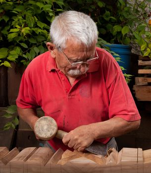 Old woodcarver working with mallet and chisel 10