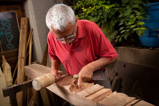 Old woodcarver working with mallet and chisel 7