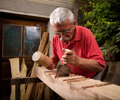 Old woodcarver working with mallet and chisel 5