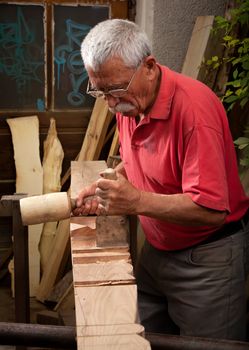 Old woodcarver working with mallet and chisel 3
