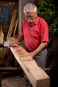 Old woodcarver working with mallet and chisel