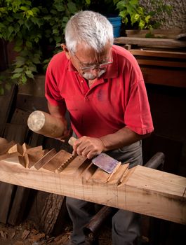 Old woodcarver working with mallet and chiesel