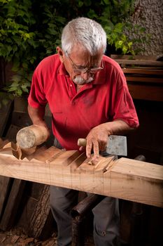 Old woodcarver working with mallet and chiesel