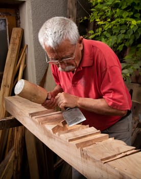 Old woodcarver working with mallet and chisel 8