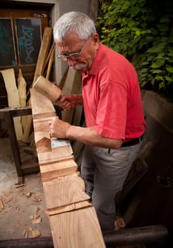 Old woodcarver working with mallet and chisel 4