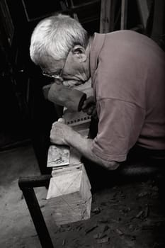 Old woodcarver working with mallet and chiesel 