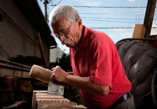 Old woodcarver working with mallet and chiesel