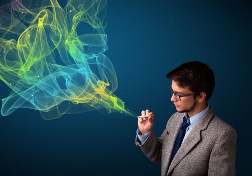 Handsome young man smoking cigarette with colorful smoke