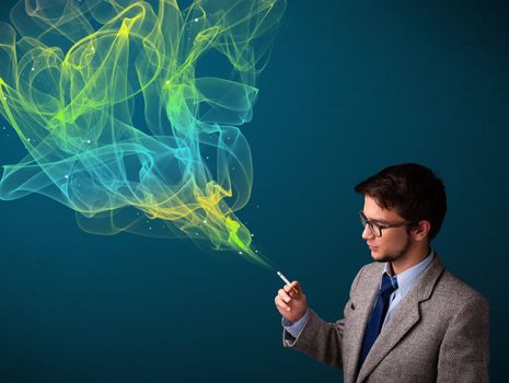 Handsome young man smoking cigarette with colorful smoke