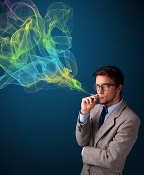 Handsome young man smoking cigarette with colorful smoke