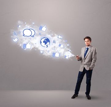 attractive young man holding a phone with social media icons in abstract cloud