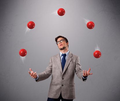 handsome young man standing and juggling with red balls