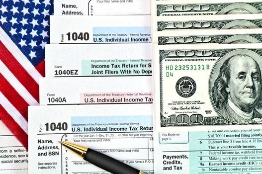 Tax forms 1040 with U.S. flag, pen and money.