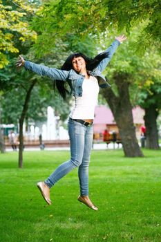 photo of young woman jamping on a grass