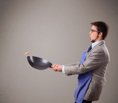 Attractive young man holding a black frying pan