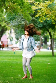 photo of young woman jamping on a grass