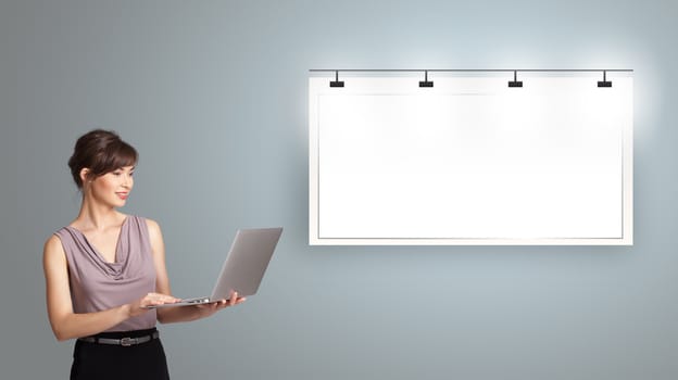 beautiful young woman holding a laptop  and presenting modern copy space