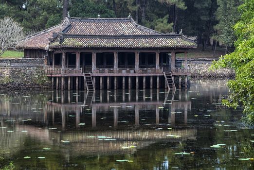 Reflection of Chinese styly wooden structure set in park like environment.