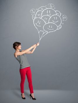 Happy young woman holding smiling balloons drawing