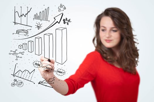 Young business woman drawing various diagrams on whiteboard