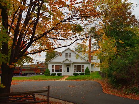 A home with fall colors of a tree in the foreground