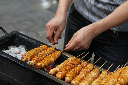 Spicy barbecued tofu kebabs being prepared by street food vendor in Chinese market
