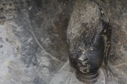 Detail of carved stone Buddha at Longmen Grottoes, a UNESCO World Heritage Site in Luoyang, China
