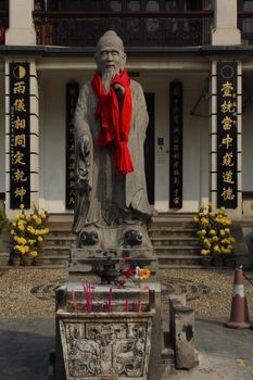 Statue of Confucius with burning incense in Chinese temple
