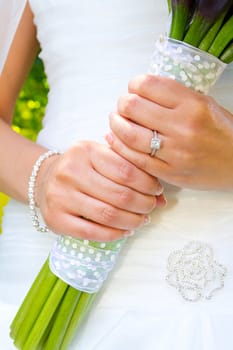 A beautiful bride in her white wedding dress holds her bouquet of flowers on her wedding day.