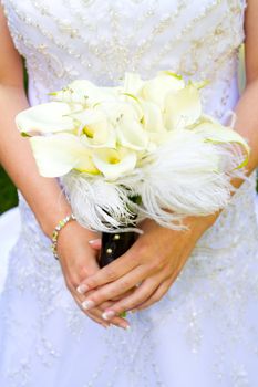 A beautiful bride in her white wedding dress holds her bouquet of flowers on her wedding day.