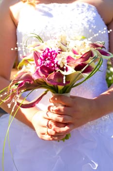 A beautiful bride in her white wedding dress holds her bouquet of flowers on her wedding day.