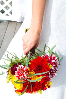 A beautiful bride in her white wedding dress holds her bouquet of flowers on her wedding day.