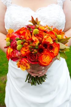 A beautiful bride in her white wedding dress holds her bouquet of flowers on her wedding day.