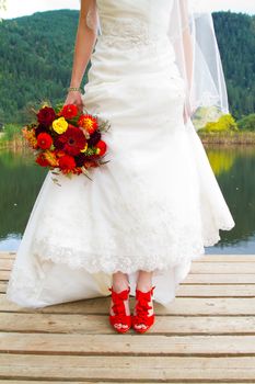 A bride wearing her beautiful red wedding shoes on her wedding day. They are stilettos of vibrant color.