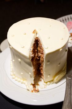 A cake with a big slice taken out by the bride and groom after they cut the cake.