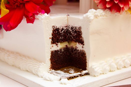 A cake with a big slice taken out by the bride and groom after they cut the cake.