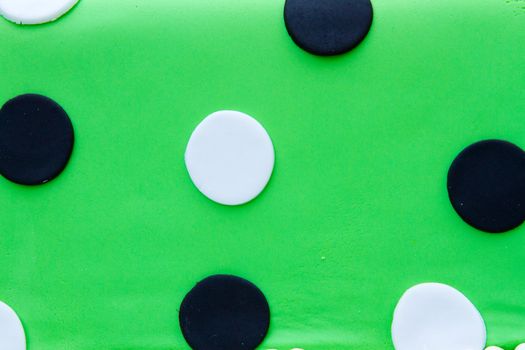 A very non-traditional wedding cake with white, green, and black and polkadots on it at the reception for a bride and groom.