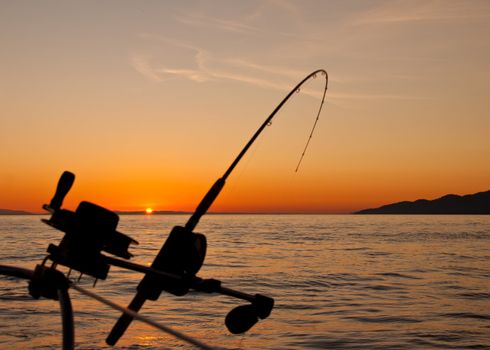 Taken just off the coast of Vancouver Island the silhouette of a down rigging fishing rod at sunset.