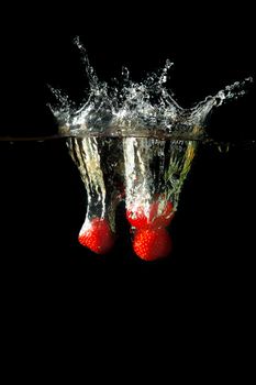 Colored red paprika in water splashes on black background