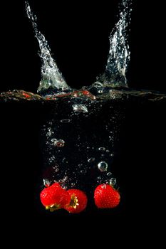 Colored red paprika in water splashes on black background