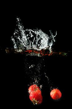 Colored red paprika in water splashes on black background