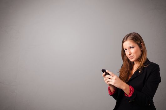 attractive young lady standing and holding a phone with copy space